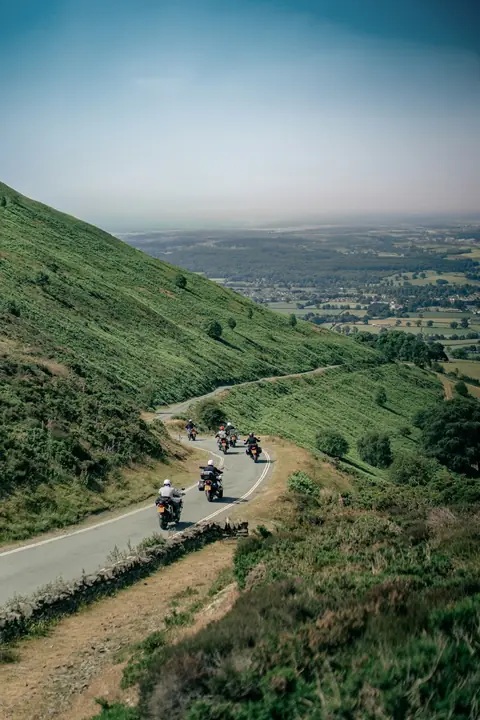 Cinq motos montent une petite route à flanc de colline au-dessus d'une vallée